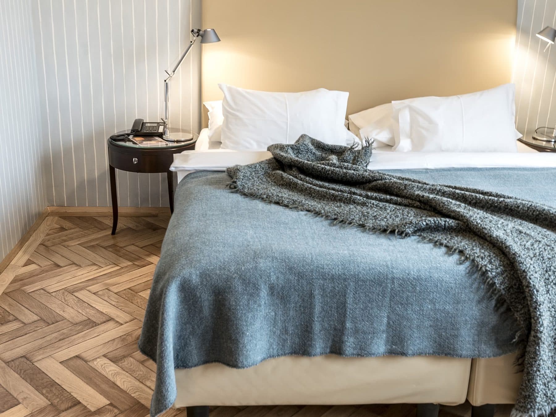Bed with grey throw, pale walls and parquet floor in room 32 at Altstadt Vienna.