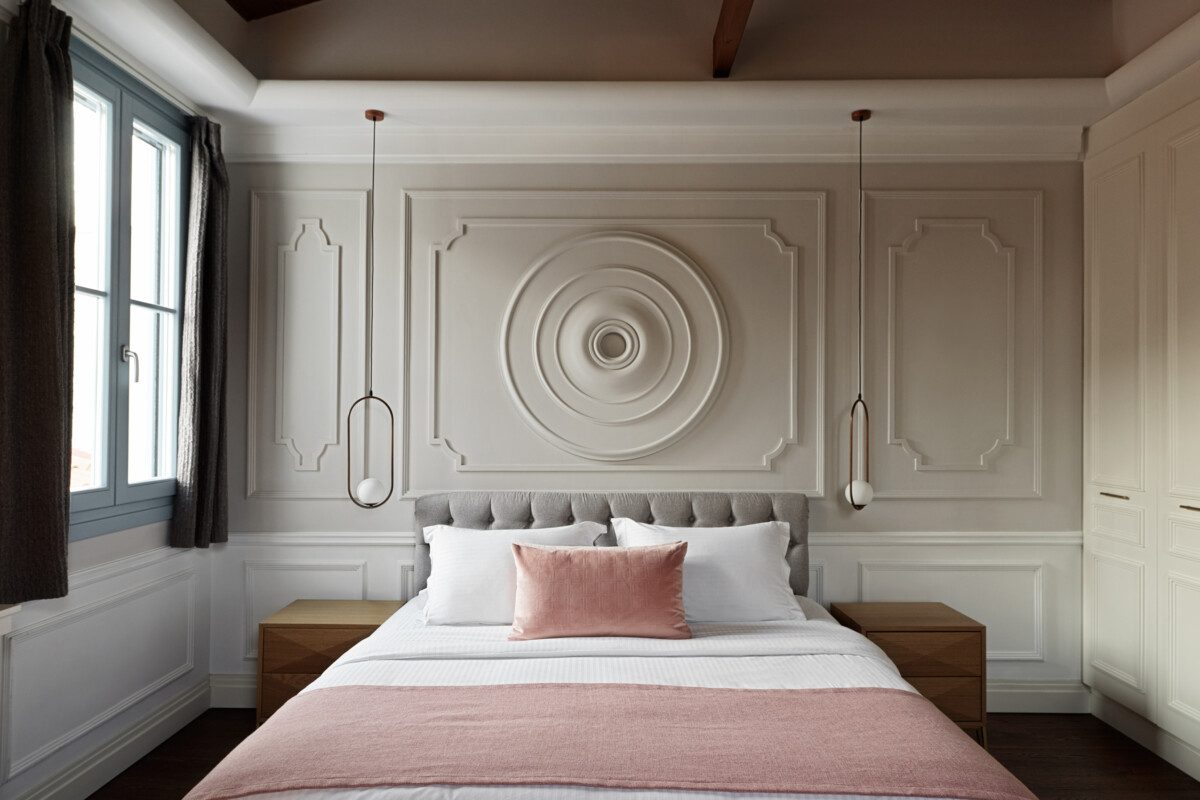 Bed with pink throw below a circular decorative wall panel in the Iconic Suite.