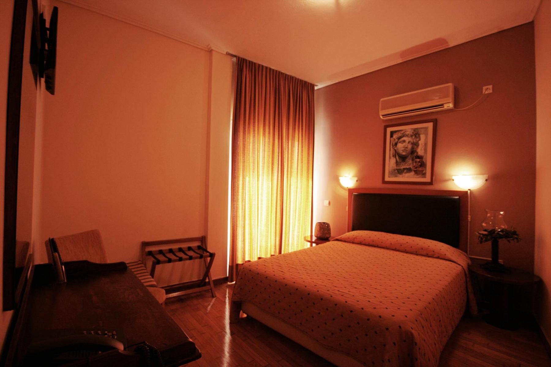 Double bed with orange cover and curtains in Adams Hotel’s view-room gallery.