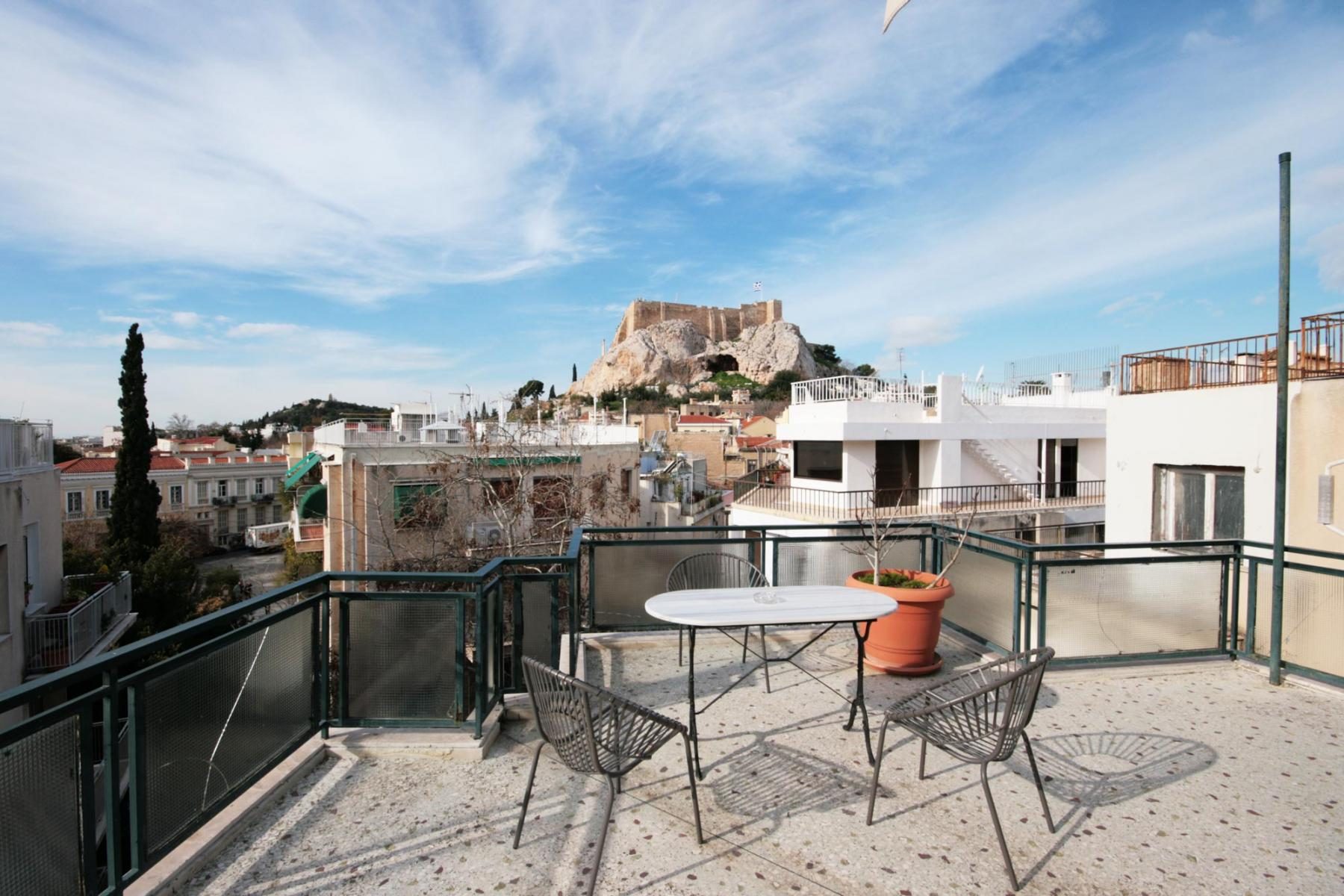 Outdoor table and chairs on a railed space facing the Acropolis.