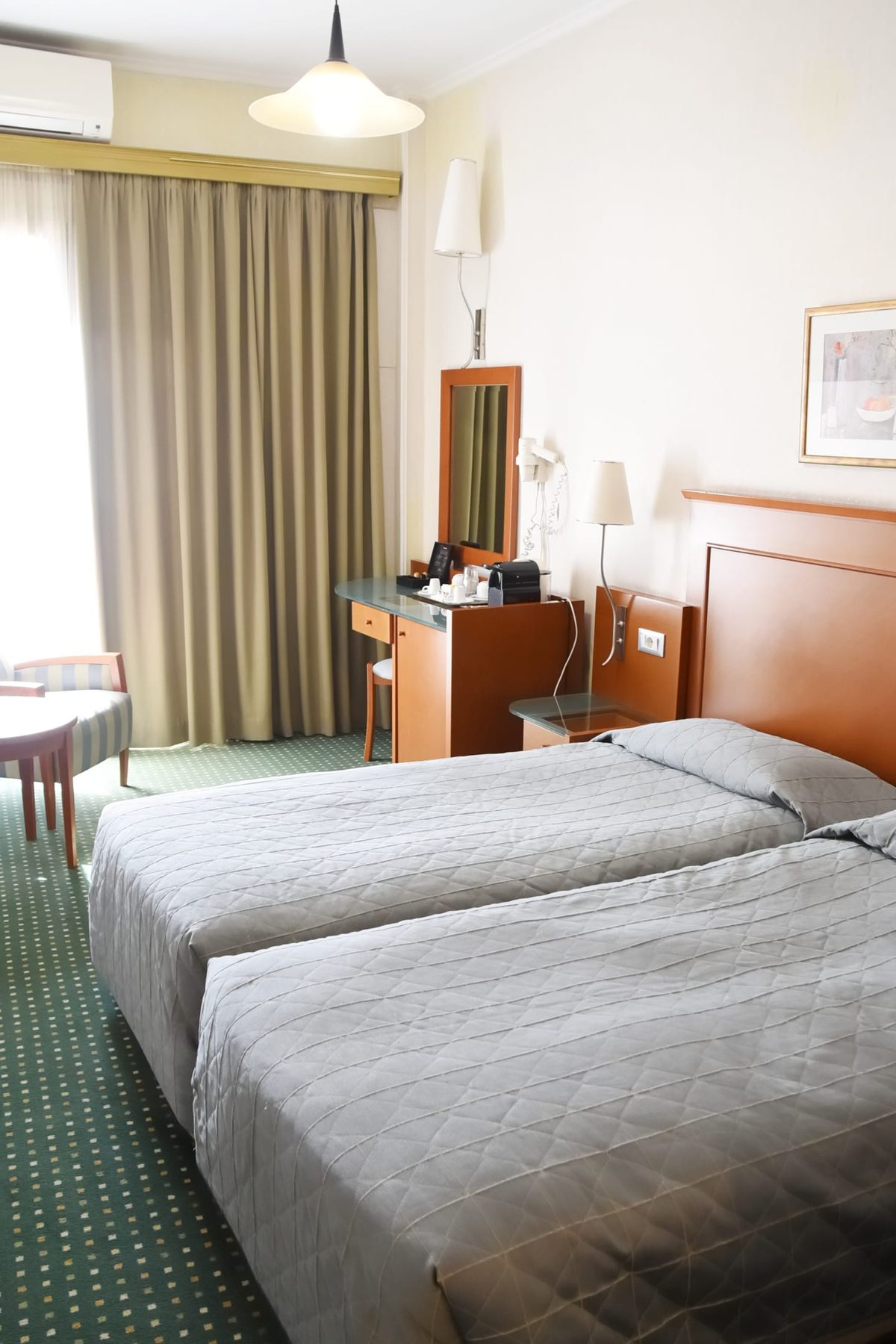 Two separate beds beneath wooden headboards in Adrian’s Acropolis View gallery.