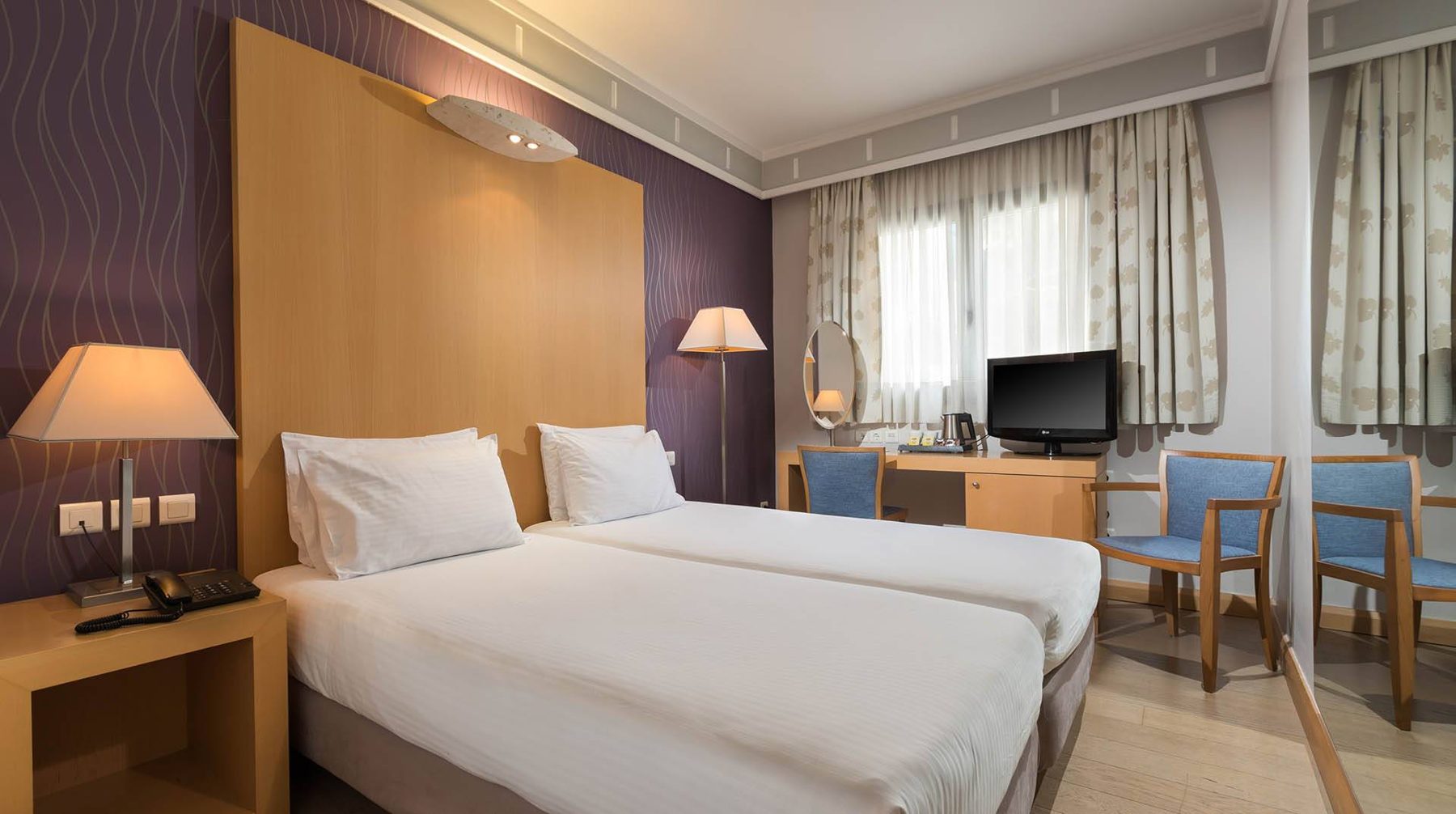 Two separate beds, desk and window in Central Athens Hotel’s Family Room gallery.