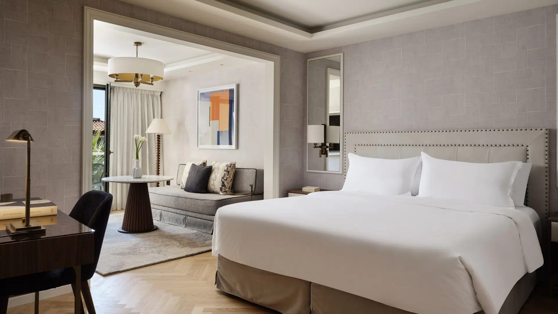 White bed beside an open sitting area in an Electra Palace Junior Suite.