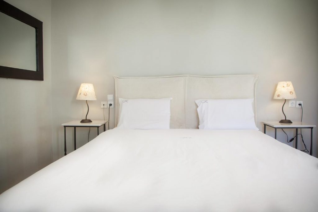 White bed, bedside lamps and wall mirror in Kimon’s Studio category image.