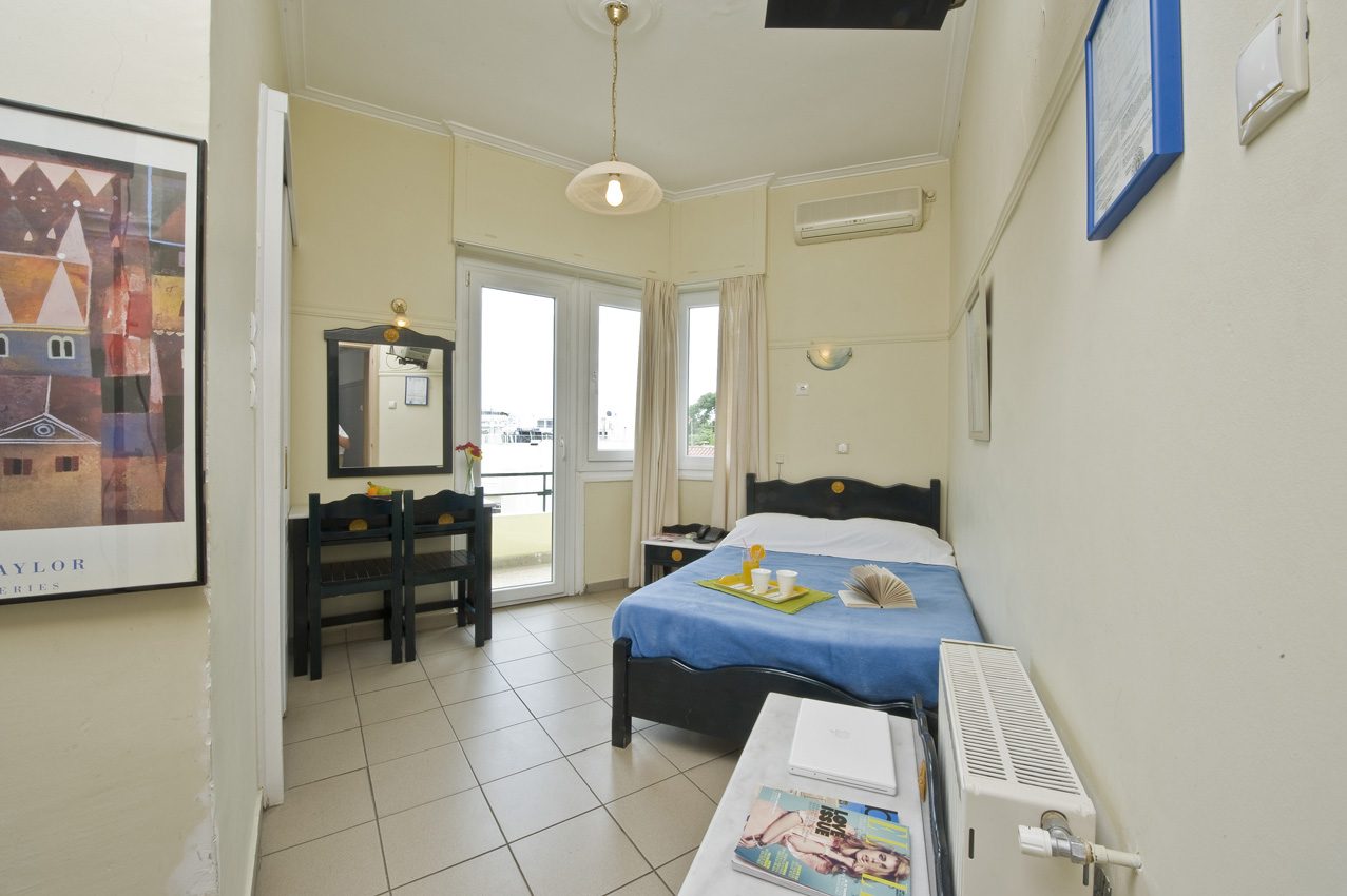 Double bed with blue cover, desk and balcony doorway in a Standard Double.