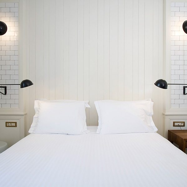 Double Economy bedroom at Praktik Bakery, with white panelling and reading lamps.