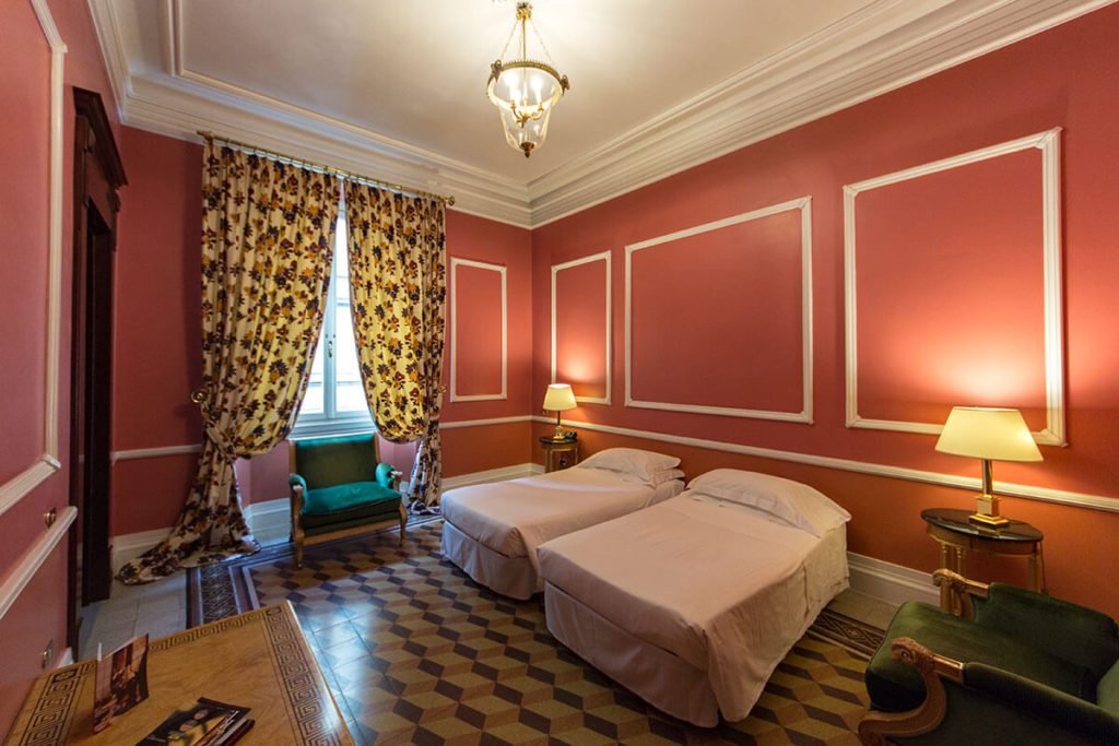Two single beds in a red-walled room with patterned curtains.