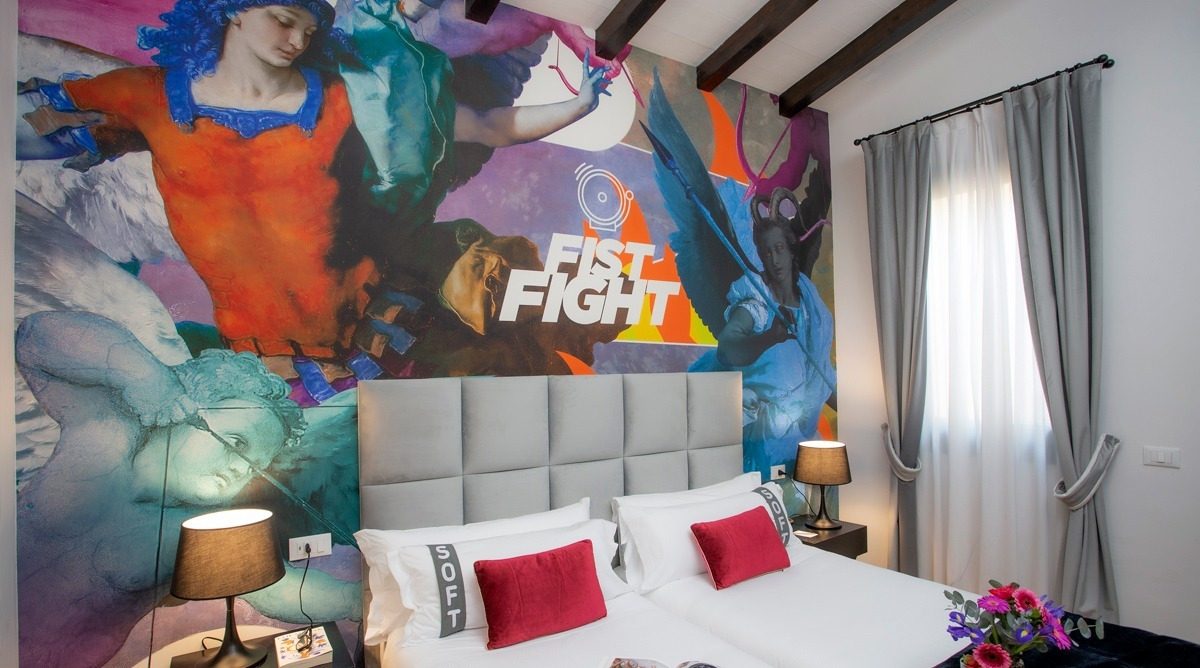 Bedroom with colourful mural art, grey headboard and exposed ceiling beams.