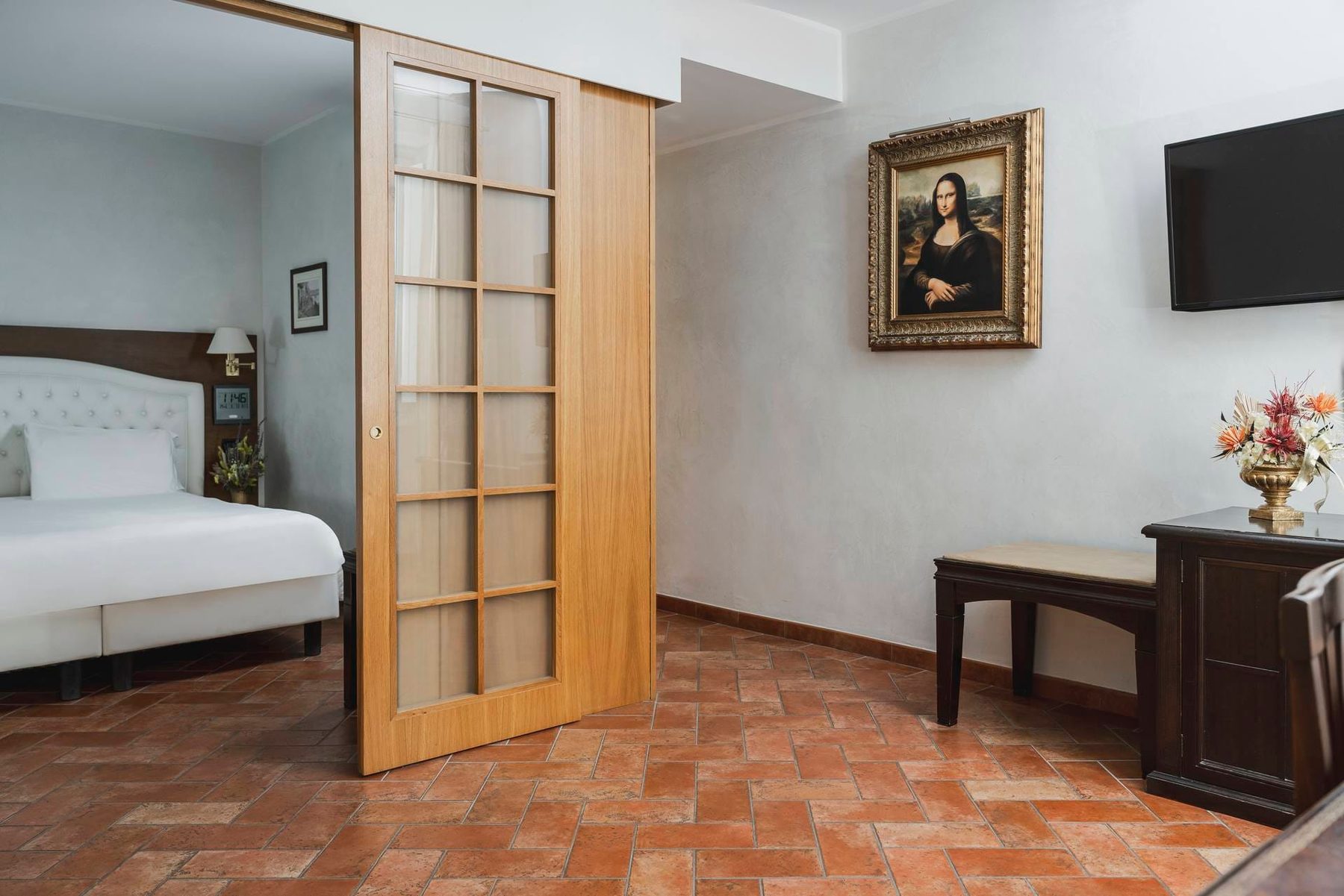 Open wooden sliding door between a bedroom and a sitting area with a desk.