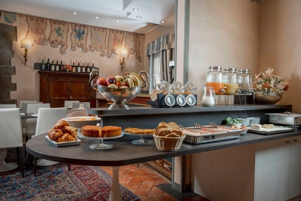 Breakfast buffet with fruit, pastries and drinks beside dining tables.