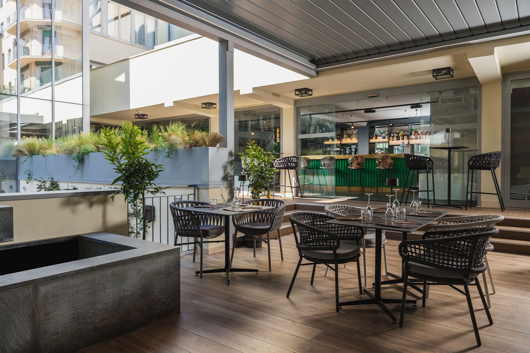 Dining tables and woven chairs beneath a covered courtyard roof.