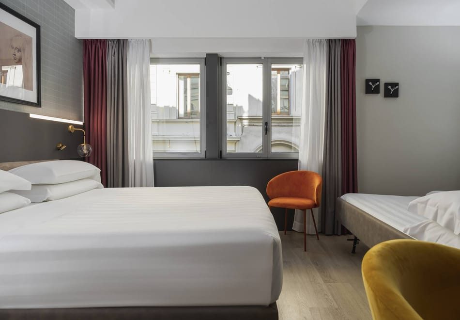 Main bed and additional sleeping space in a grey room with burgundy curtains.