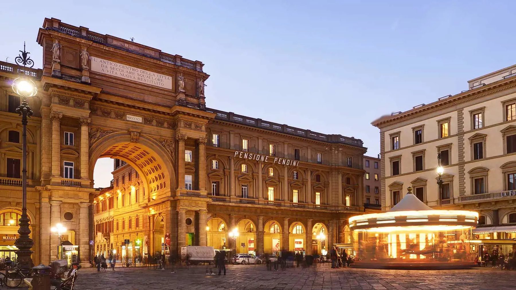 Hotel Pendini’s building beside the square’s arch and an illuminated carousel.