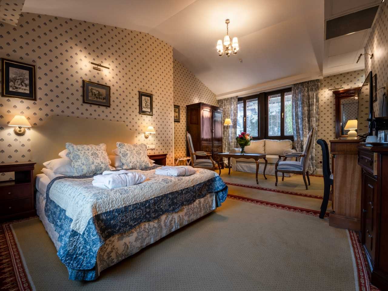 Gródek Deluxe Double room with patterned walls and window-side seating.