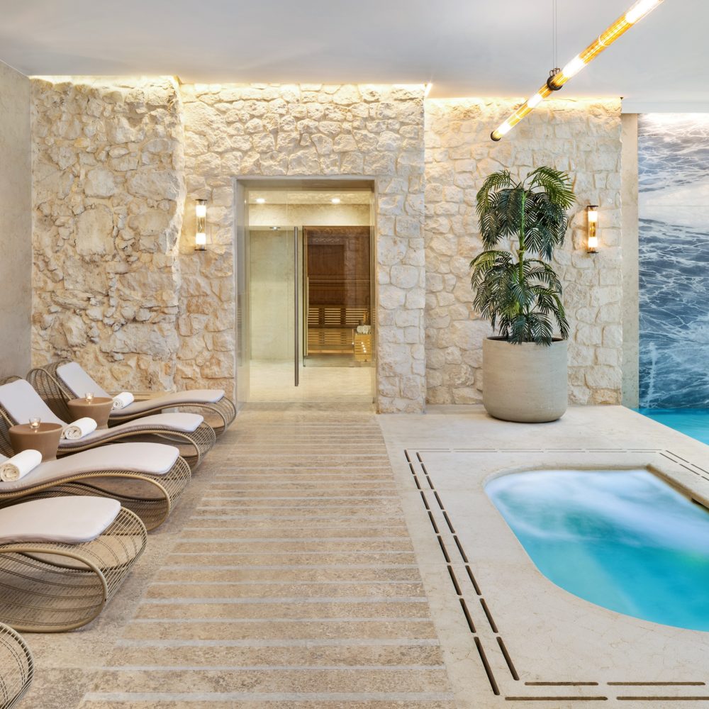Loungers beside stone walls and water in H15 Palace’s wellness area.