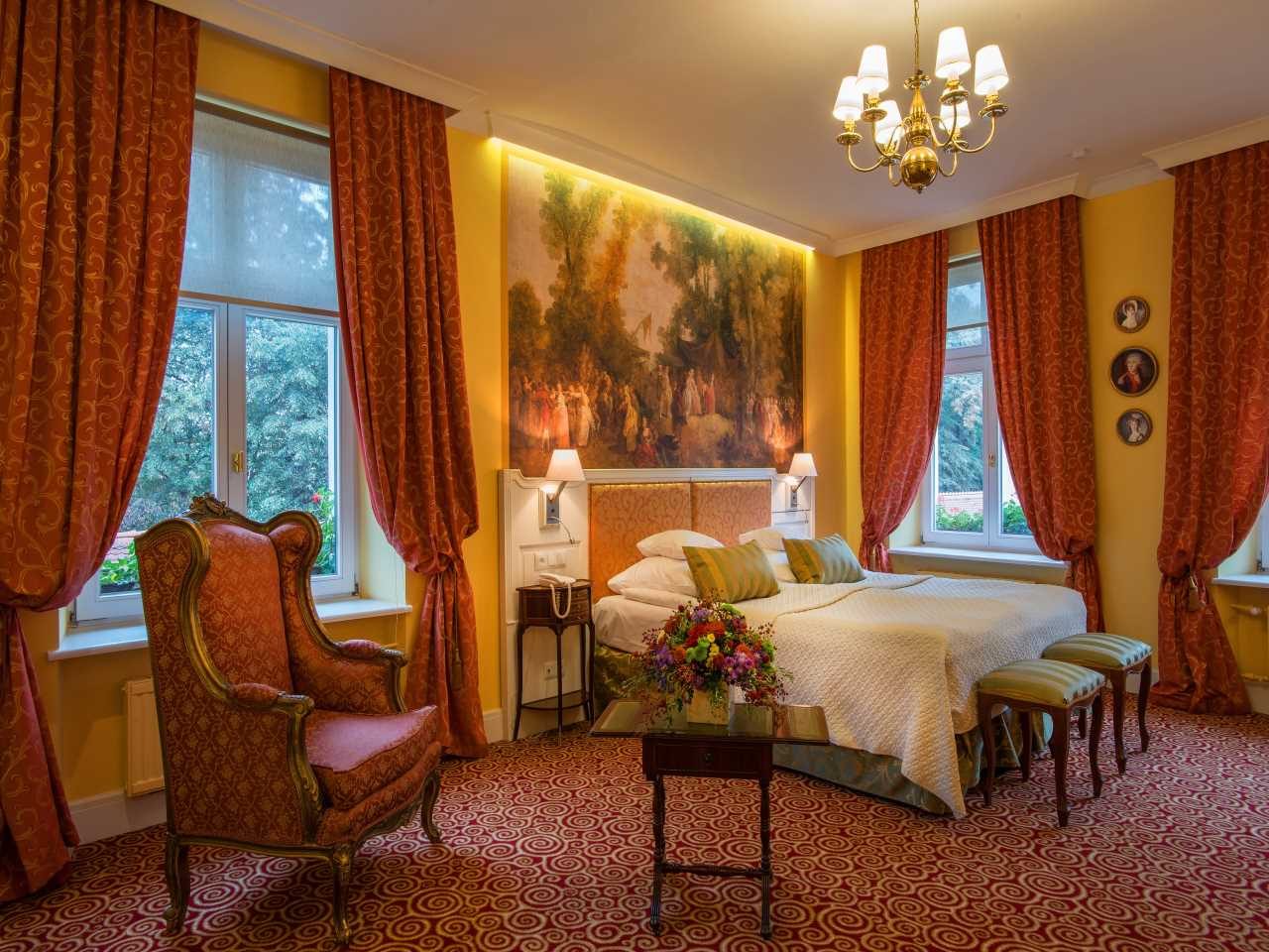 Superior Double bedroom at Hotel Polski with red curtains and patterned armchairs.