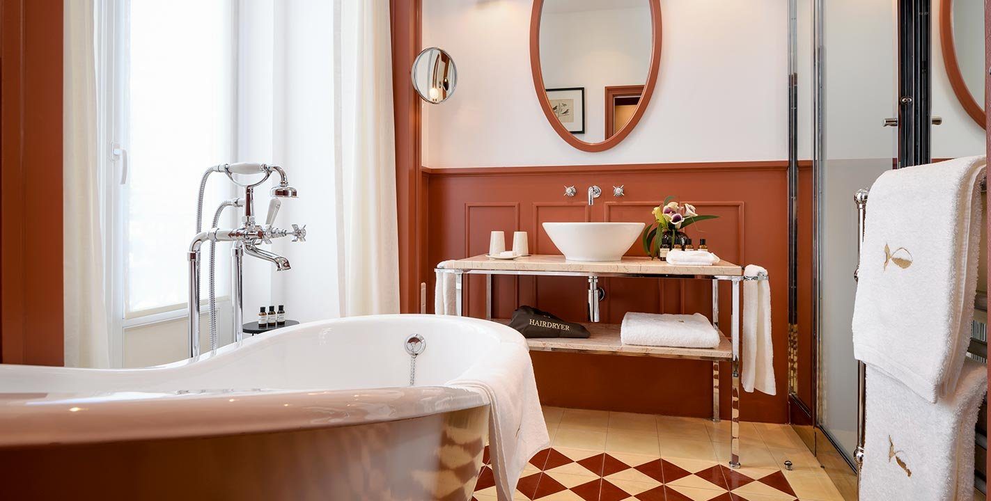 Roll-top bath and separate glass shower in a Bairro Alto Hotel Prestige Chiado bathroom.