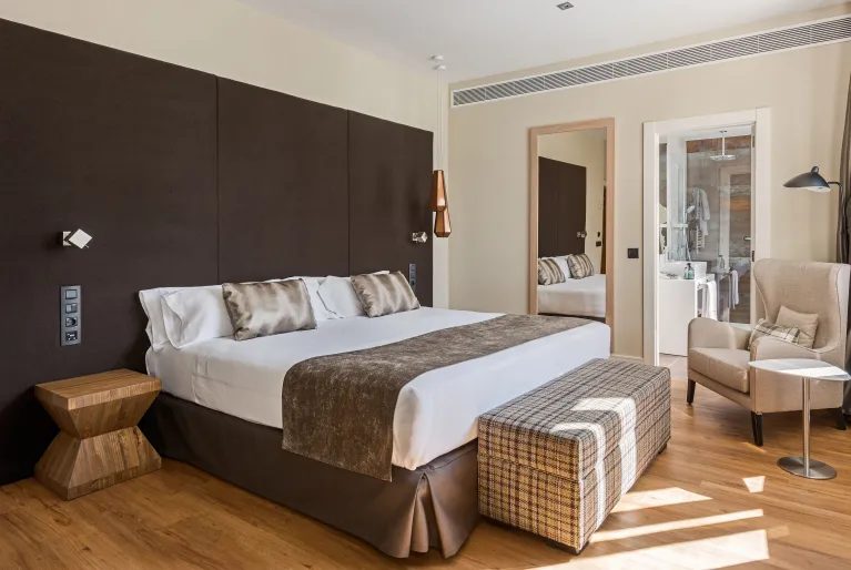 Bedroom with timber headboard and upholstered bench at Catalonia Gran Vía Madrid.