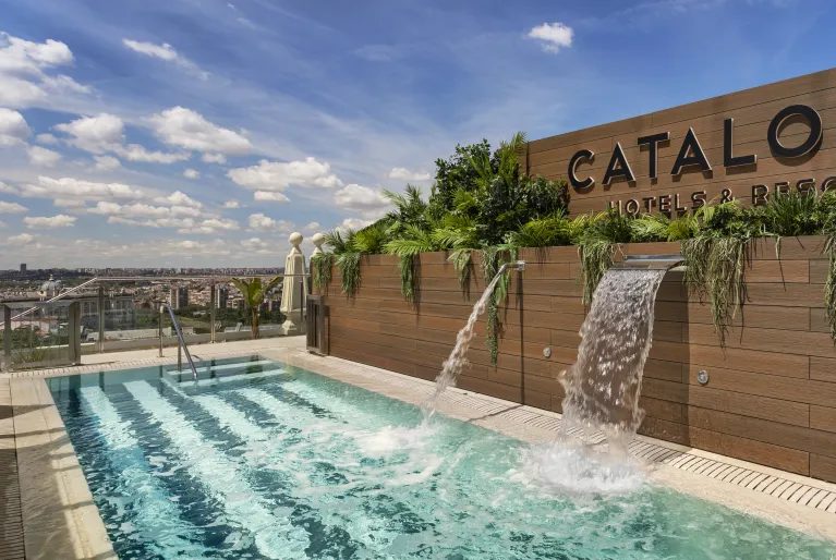 Rooftop swimming pool with water jets and Catalonia sign at Catalonia Plaza España.