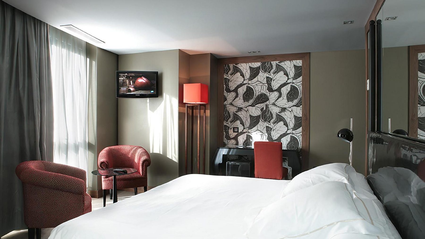 Bed and red armchairs beside the window in an Inhala panoramic room.