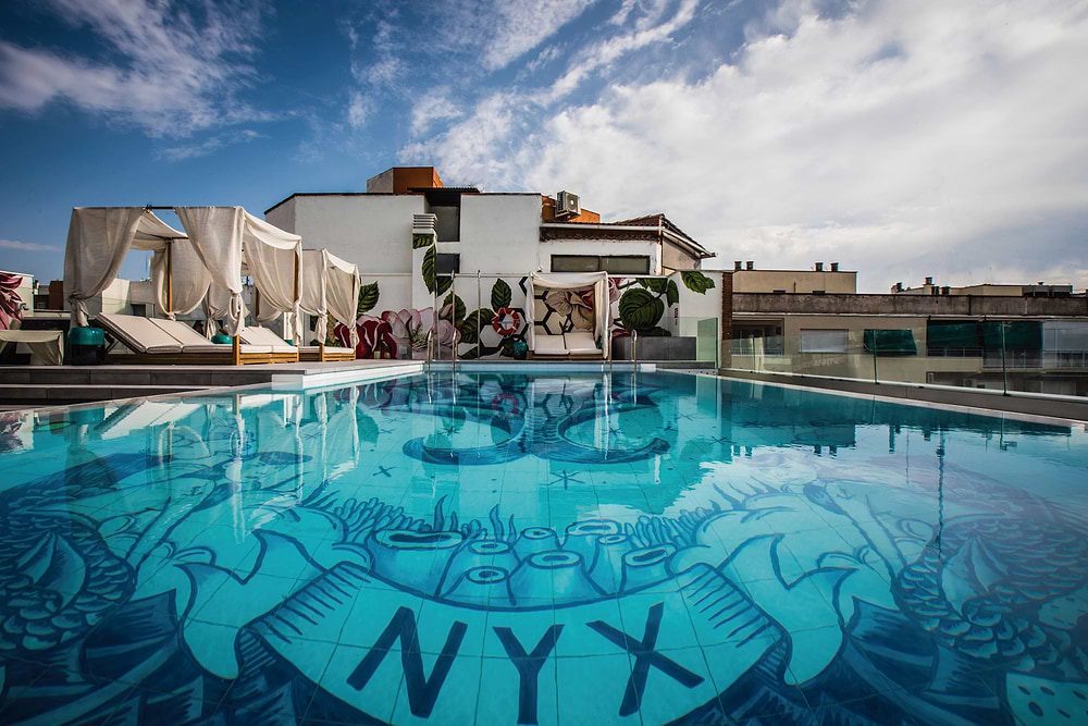 NYX Madrid rooftop swimming pool with patterned floor and white cabanas, official 2024 press image.
