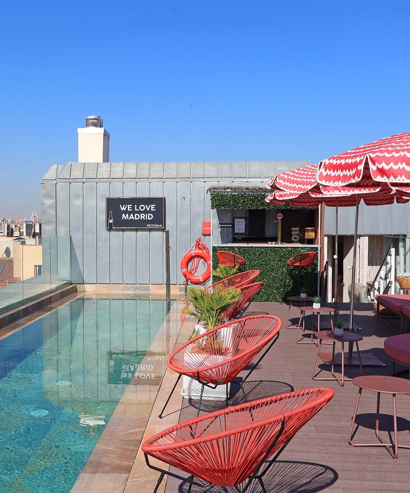 Narrow rooftop swimming pool with red chairs at Pestana Collection Plaza Mayor.