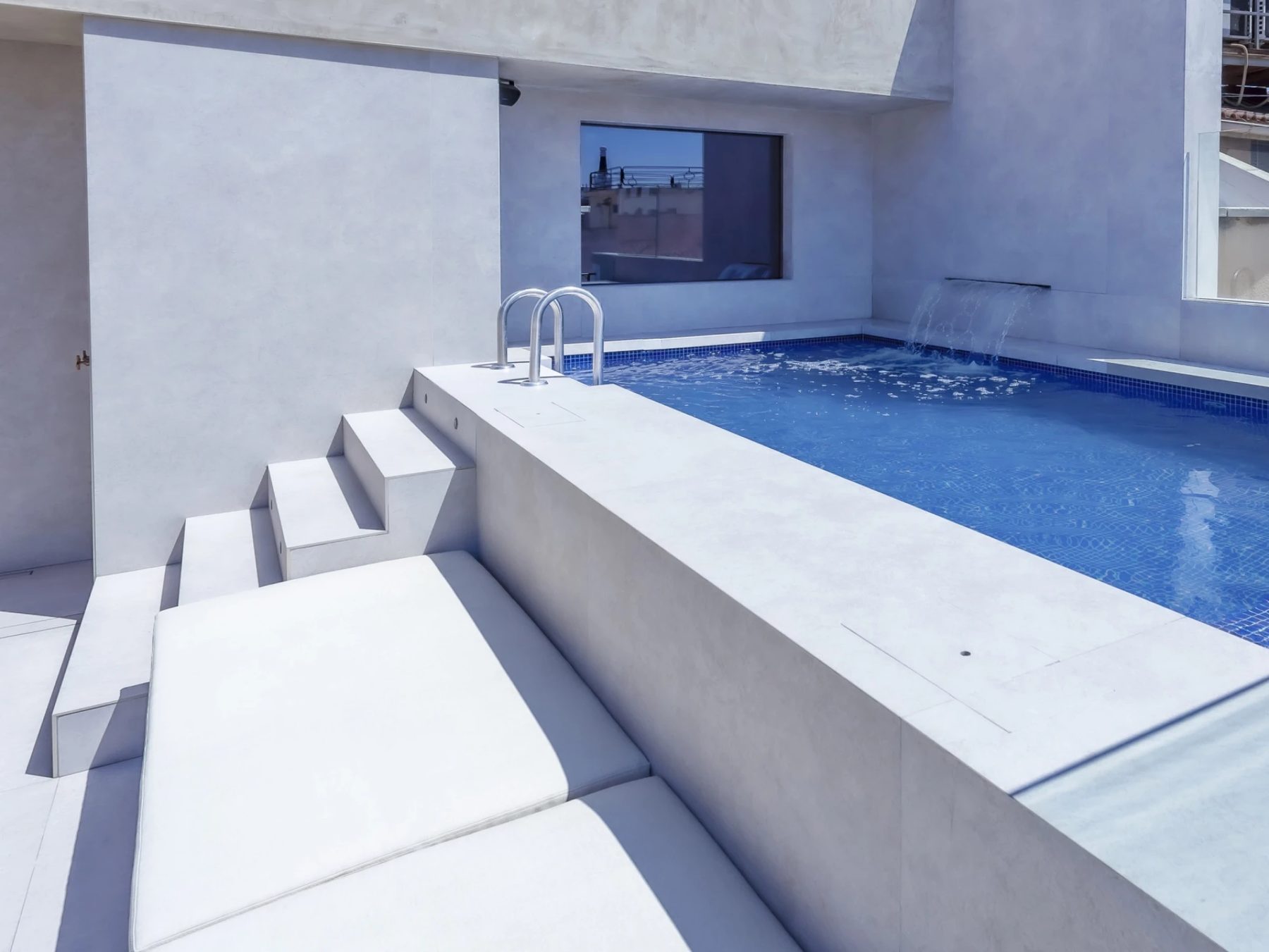 Small rooftop pool with metal ladder and adjacent steps at Hotel Villa Real.