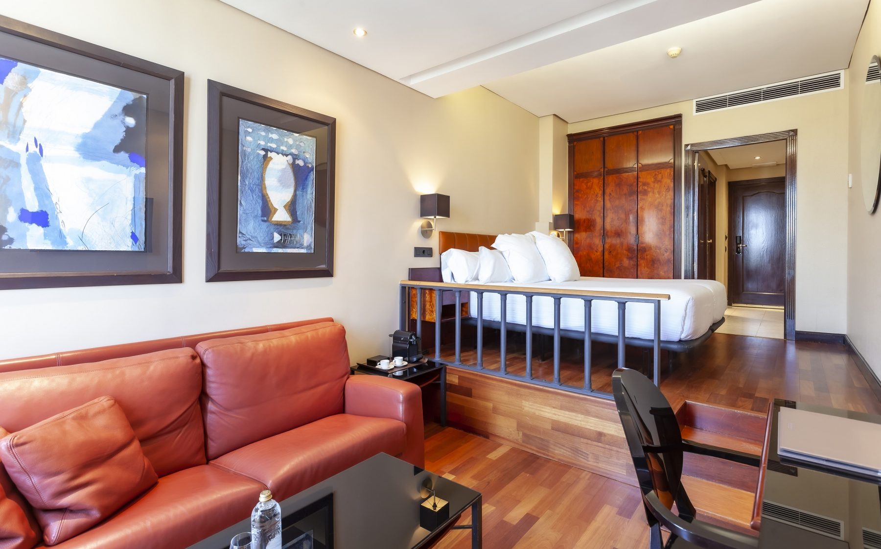 Bedroom and leather-sofa sitting area in a Villa Real Double Superior with views.
