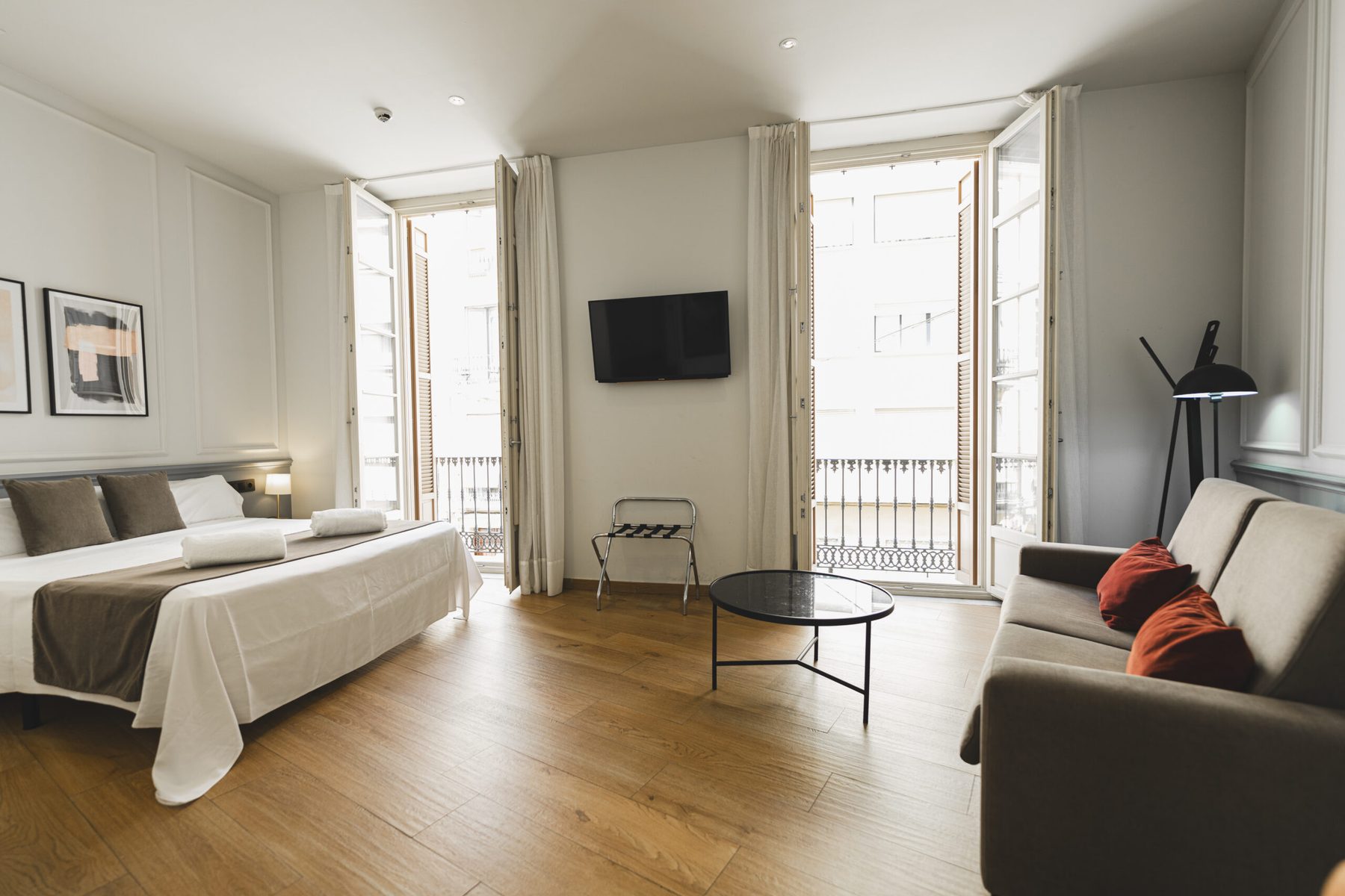 Hotel bed, sofa and two open glazed balcony doorways.