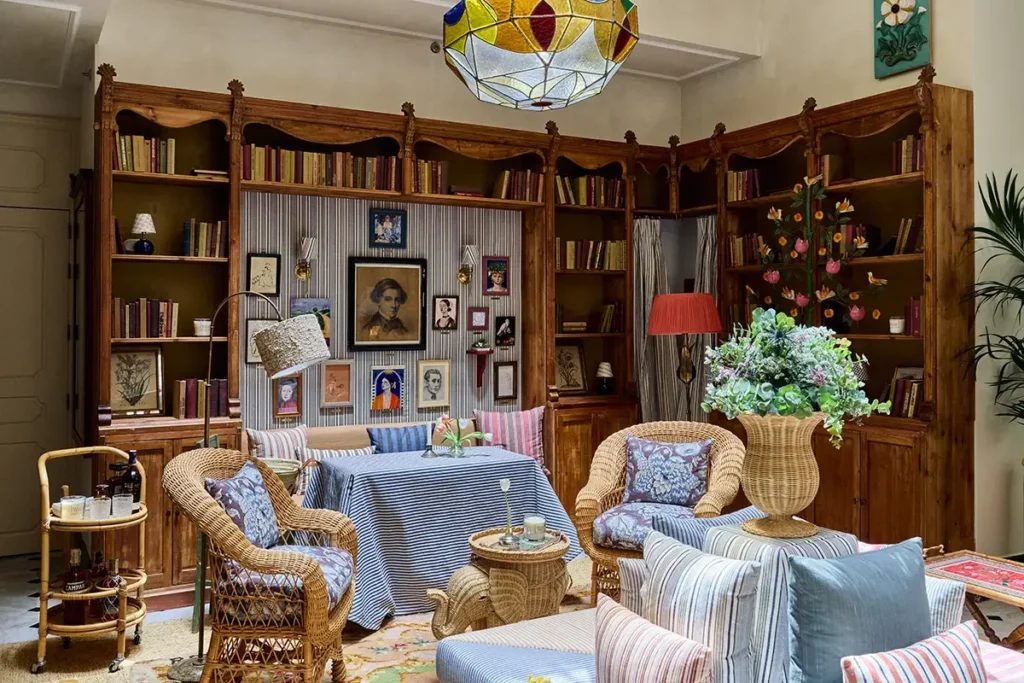 Wicker armchairs, patterned cushions and wooden bookshelves in a hotel lounge.