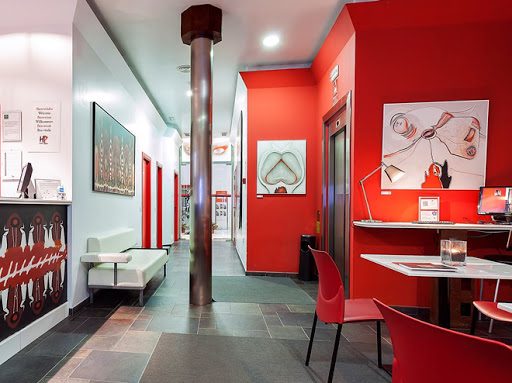 Red reception desk and walls with framed artwork and a corridor beyond.