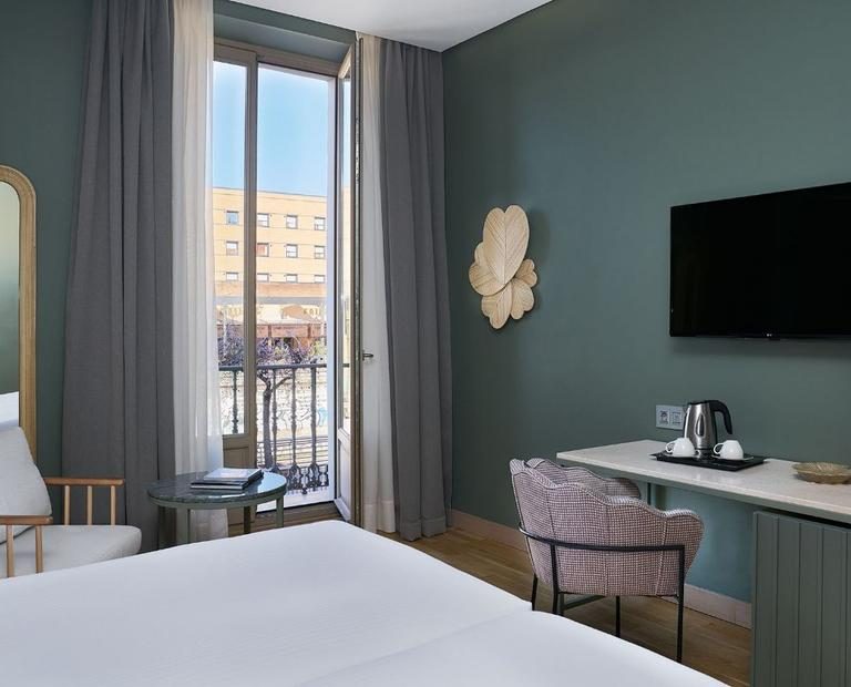 Bed, desk, blue feature wall and glazed balcony doors in a Posada del Patio room.