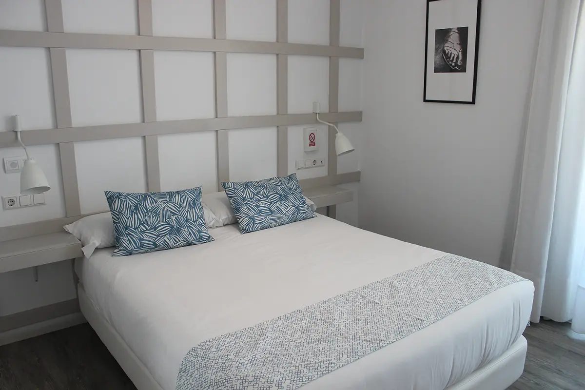 Double bed with a pale panel headboard and blue patterned cushions.
