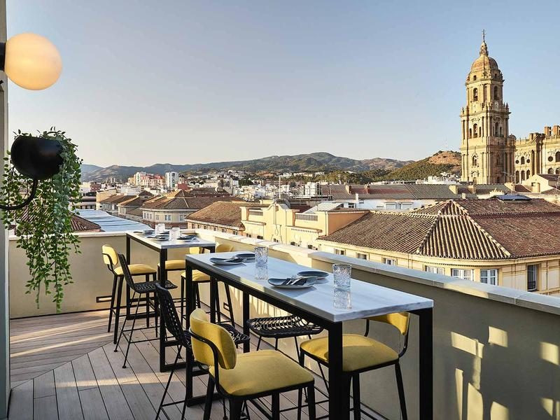 Outdoor dining tables overlooking Old Town rooftops and Málaga Cathedral.