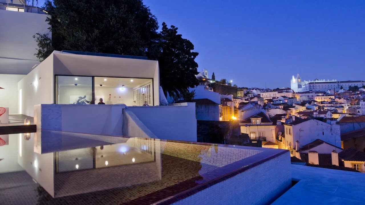 Outdoor pool and city panorama at Memmo Alfama after dusk