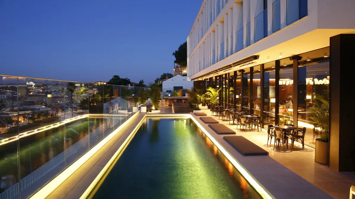 Outdoor pool at Memmo Príncipe Real with Lisbon skyline views after dusk