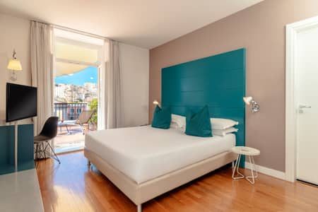 Bedroom with a turquoise headboard and a doorway opening to a terrace.