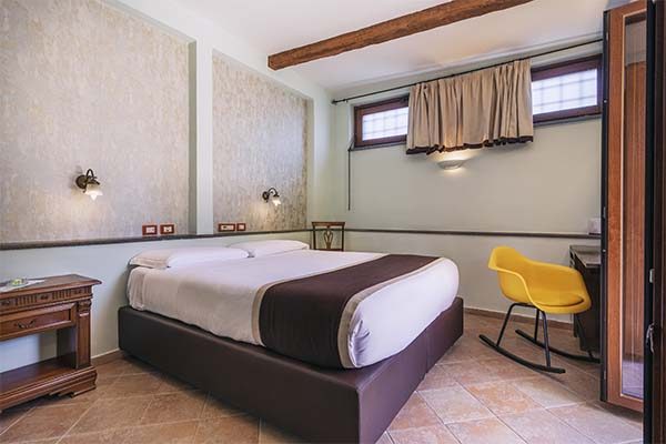 Bedroom with an exposed ceiling beam, high windows and a yellow chair.