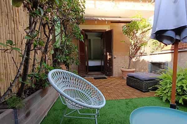 Terrace with climbing plants, woven seating and an open doorway to the bedroom.