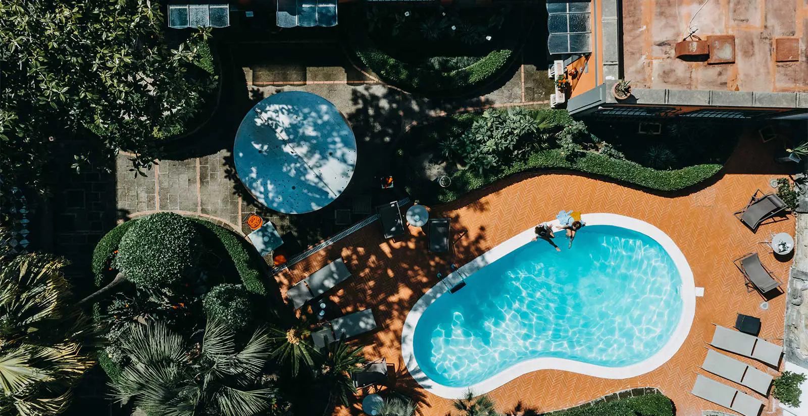 Overhead view of the curved outdoor pool and surrounding garden.
