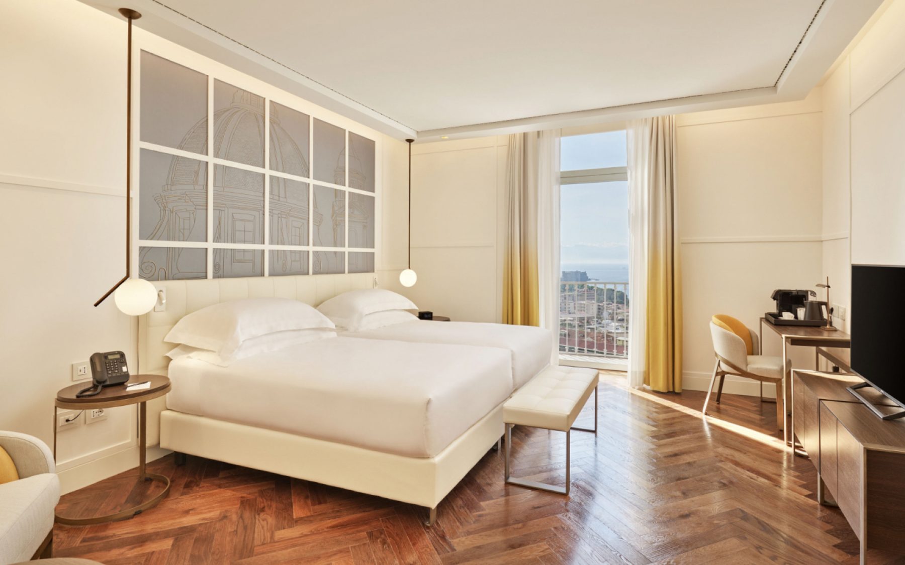 Pale bedroom with parquet flooring and a desk by the window.