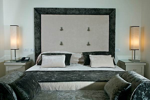 Bedroom with a tall upholstered headboard and matching bedside lamps.