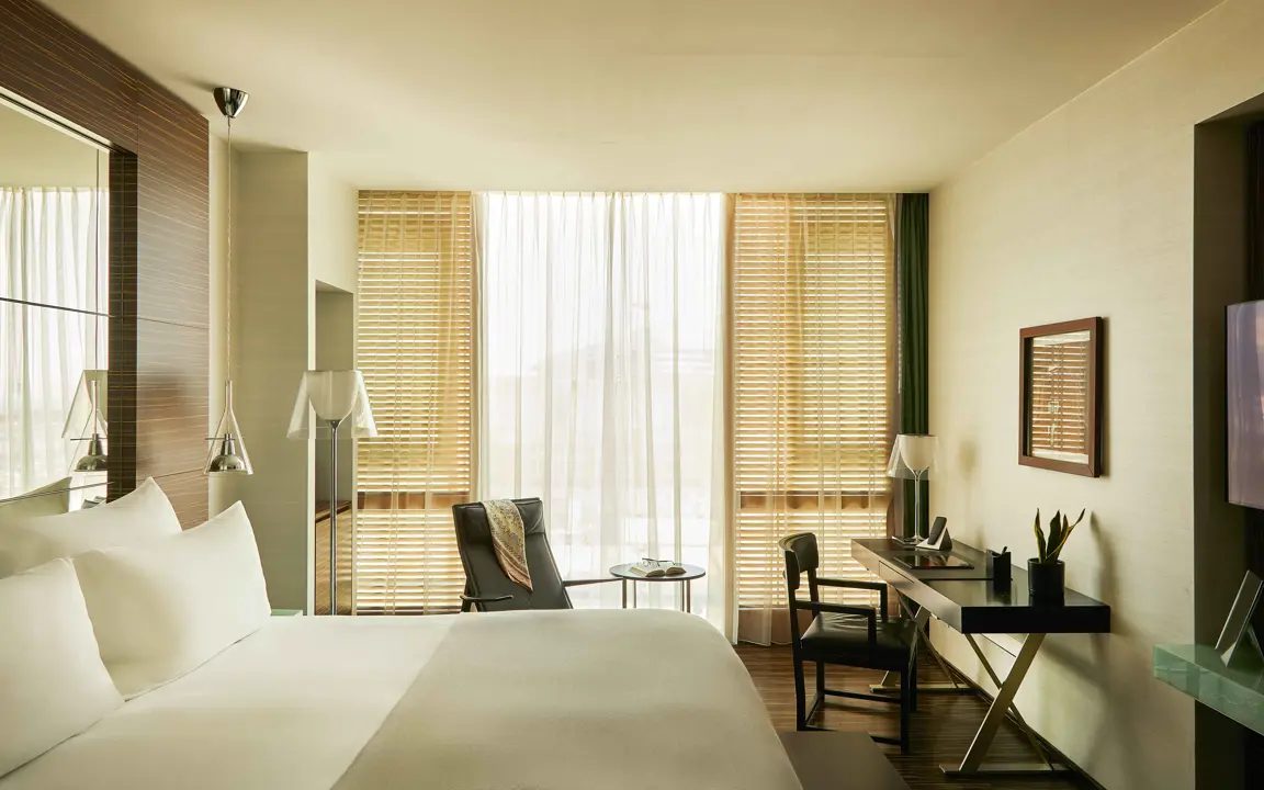 Bedroom with full-height windows, timber blinds and a writing desk.