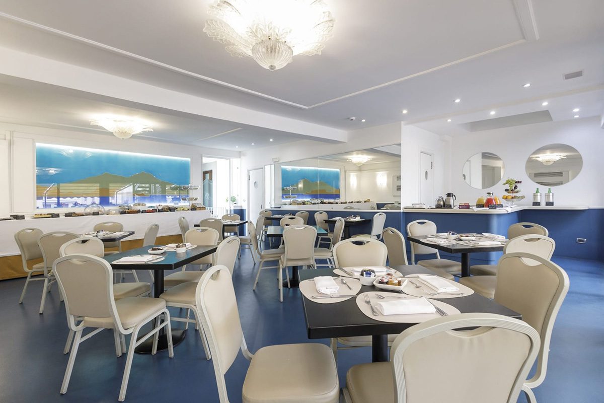 Breakfast tables and a buffet counter in a bright shared dining room.