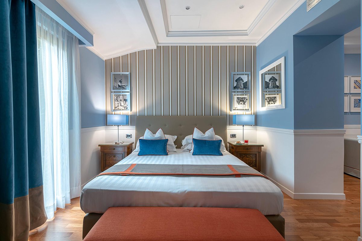 Blue bedroom with a striped headboard wall and an orange bench.