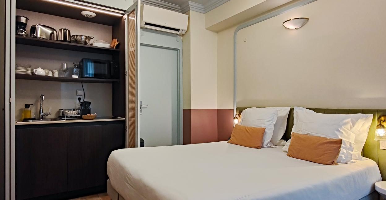 Compact kitchen cabinet beside the bed in an AMMI Vieux Nice Standard Plus studio