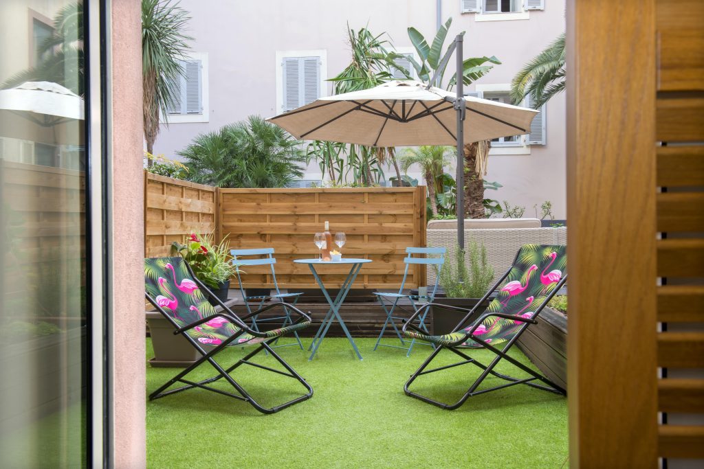 Furnished courtyard terrace with a parasol and loungers at Beau Rivage