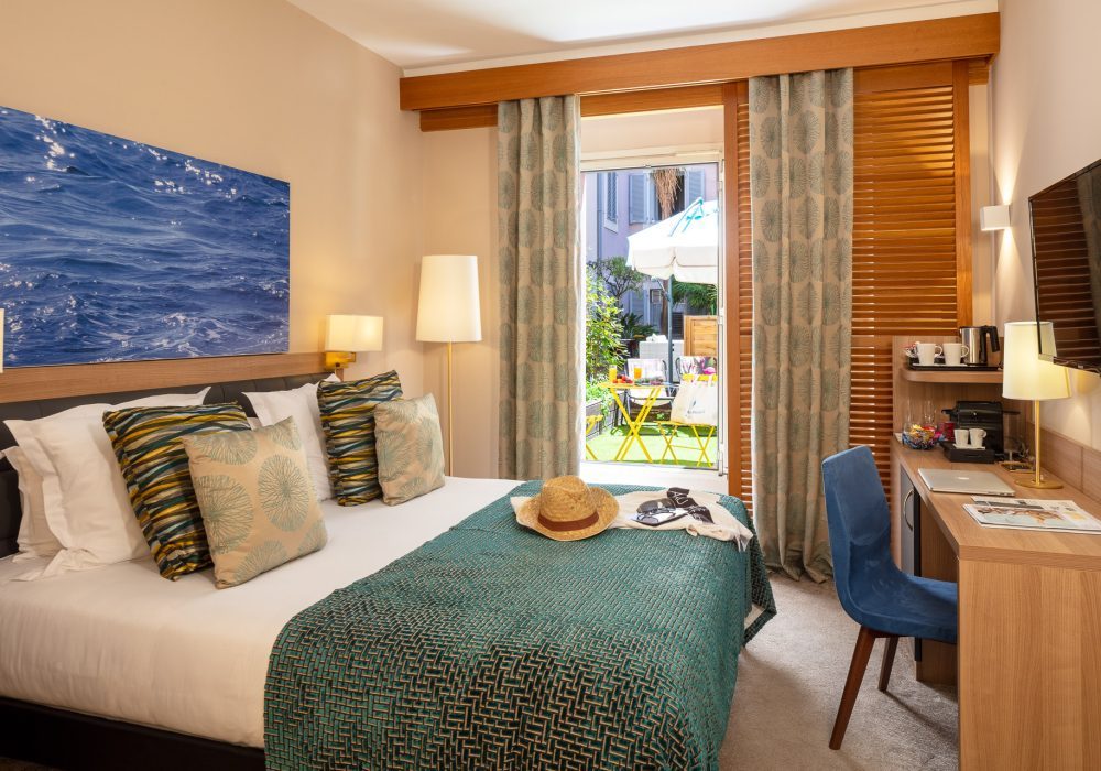 Double bed and desk opening onto a courtyard terrace at Beau Rivage