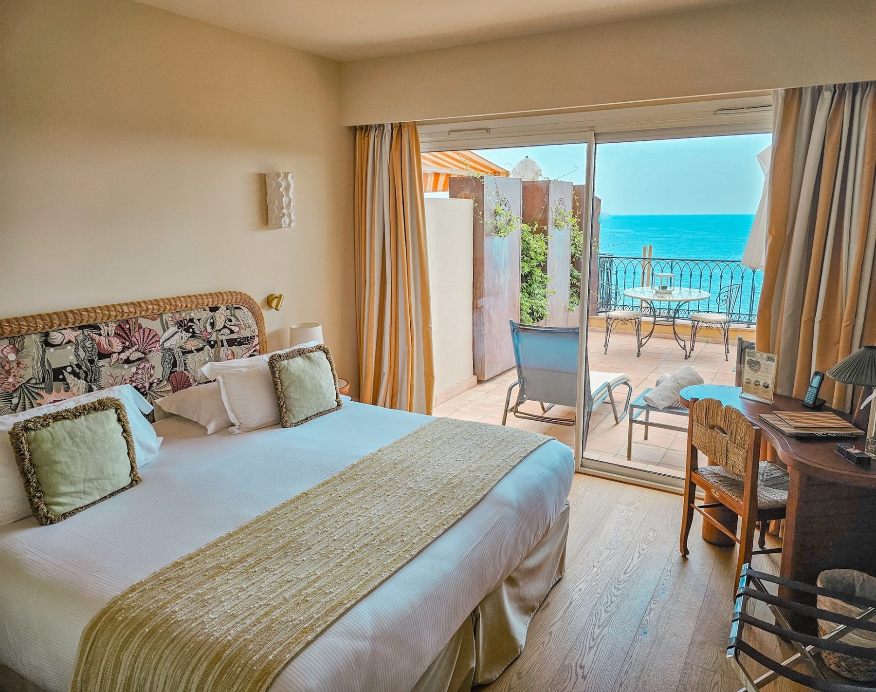 Double bed facing a furnished sea-view terrace at Hôtel La Pérouse
