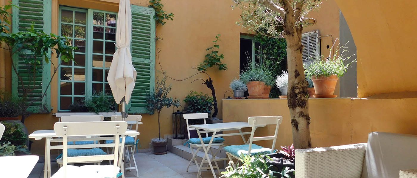 Tables and chairs among plants on the shared courtyard terrace at Hôtel Rossetti